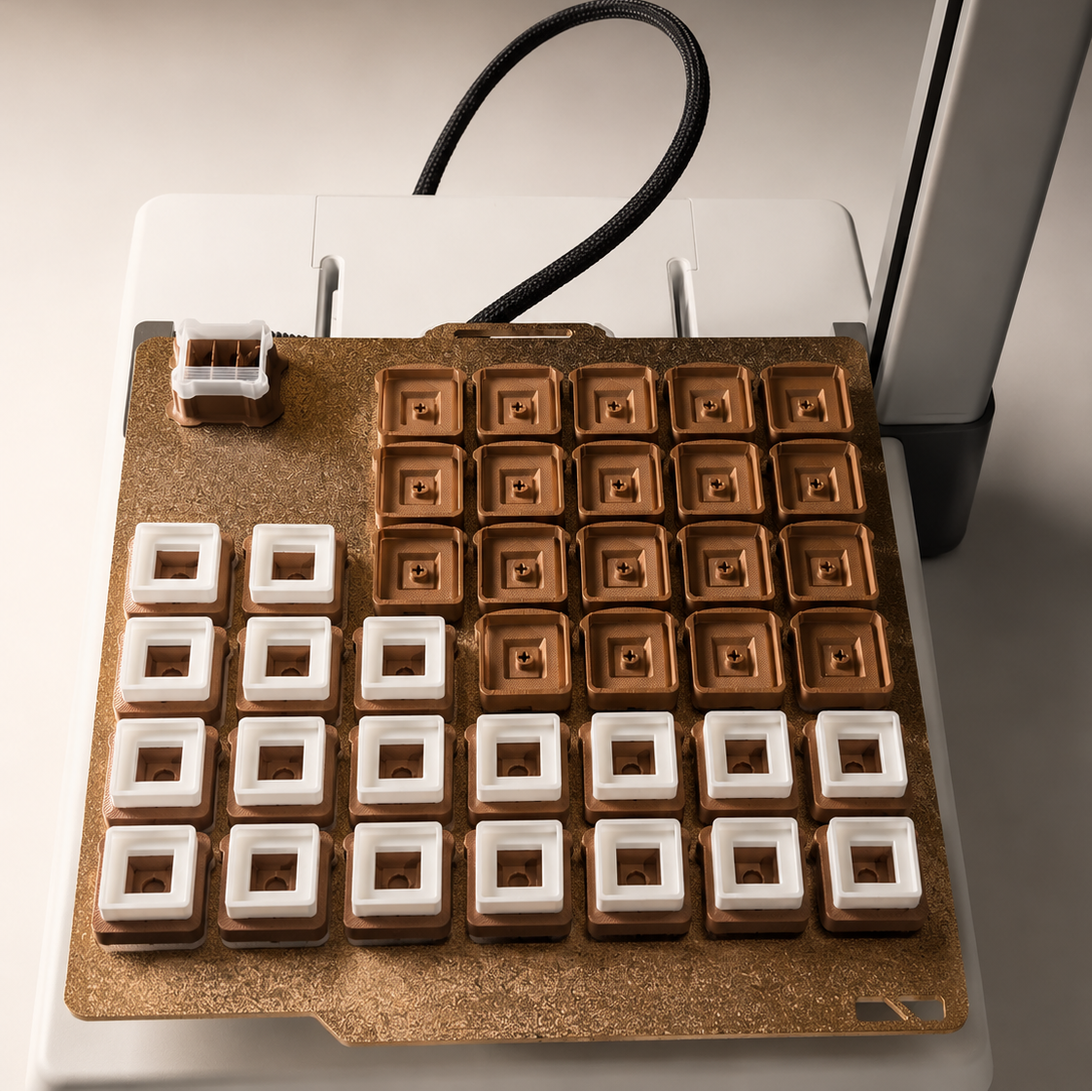 A close-up of a mechanical keyboard switch plate featuring square switches. The plate has a textured copper-colored base with a grid of switches, alternating between solid white square switches on the left and hollow square switches with visible internal gold-toned contacts on the right.